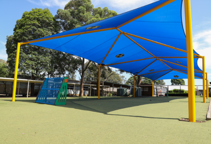 Outdoor covered learning/playground area with a bright blue shade.