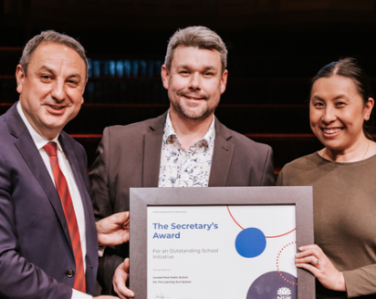 Murat Dizdar presenting an award to two teachers.