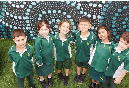 Kindergarten students smiling in a line.