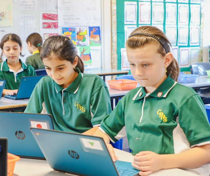 Two students in satge 3 working on school laptops in their classroom.
