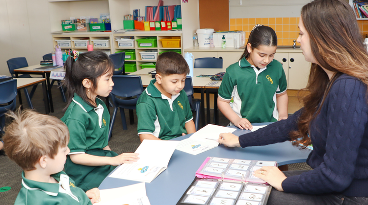 Teacher with a small groups of Stage 1 students reading books.