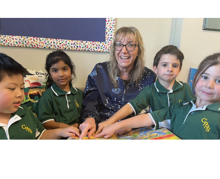 The principal sitting with some Kindergarten students.